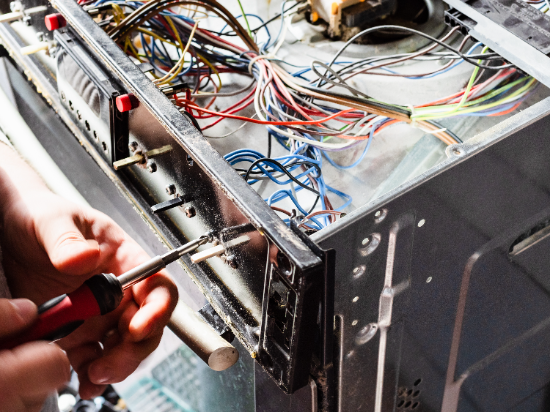 Technician using red pliers to work on computer hardware internal wiring
