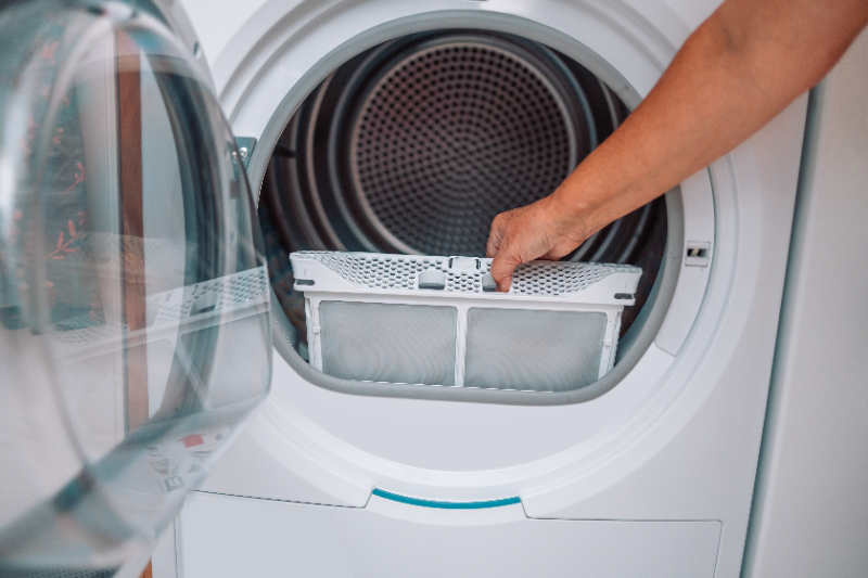 Person removing lint trap filter from open dryer door